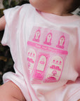 Baby wearing a pink onesie with a petite treat patisserie design.