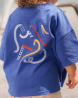 Child wearing a blue t-shirt with colorful graphic design outdoors