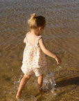 Child in a floral matching set walking in shallow water at the beach