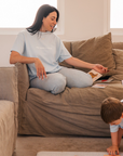 Woman sitting on a couch reading to a child in a cozy living room.