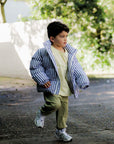 Child wearing a striped jacket outdoors with a blurred background
