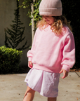 Child wearing a pink outfit with a matching hat in an outdoor setting