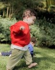 Child in a red sweater playing outdoors on grass