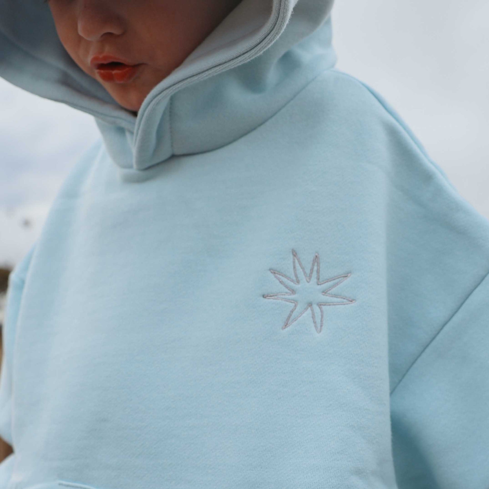 Light blue fleece jacket with a star design on a blurred natural background