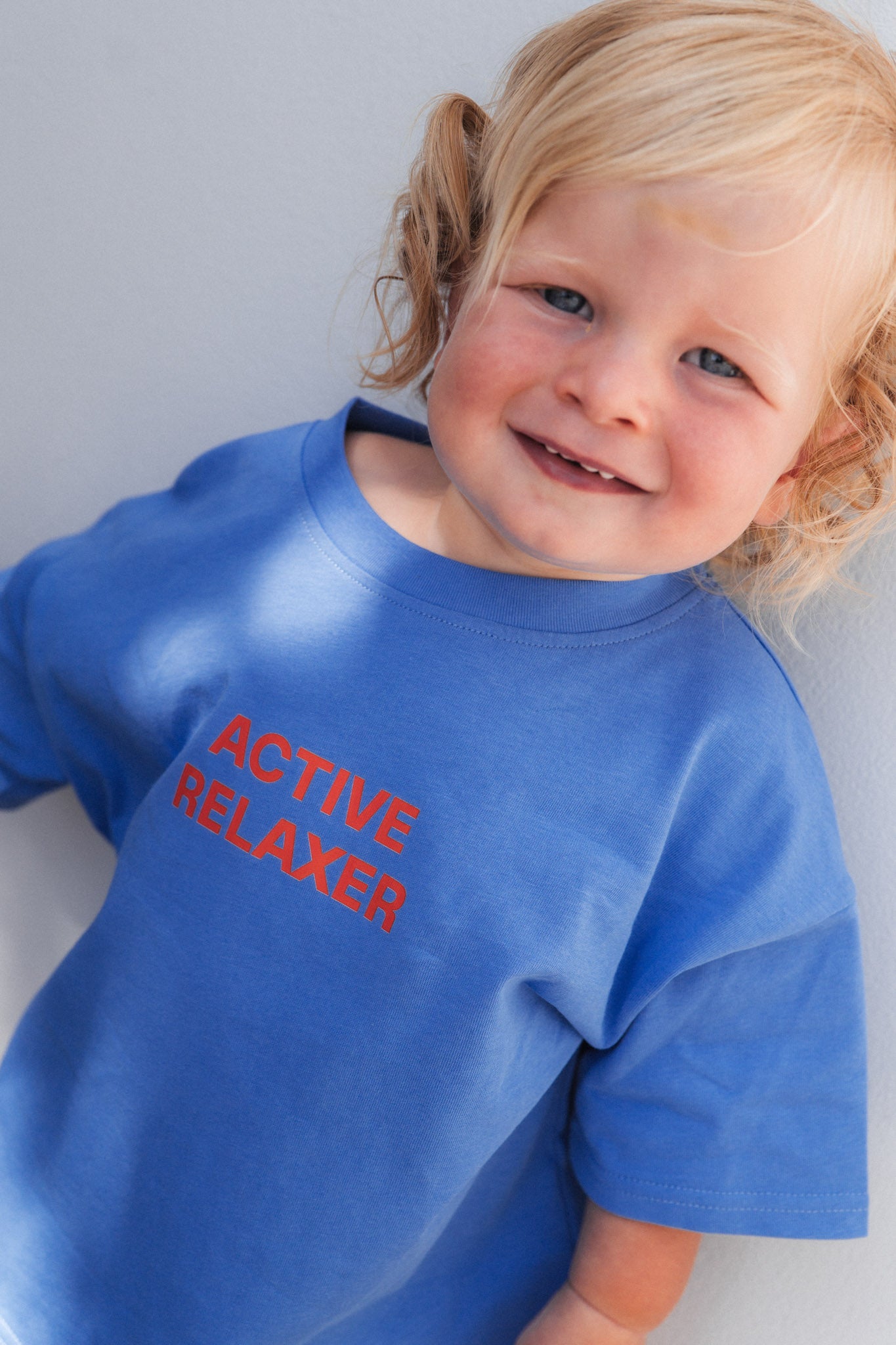 Child wearing a blue shirt with 'ACTIVE RELAXER' text on a plain background