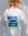 Child wearing a white t-shirt with text on the back, standing against a plain background