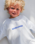 Child wearing a white t-shirt with 'BOOK LOVER' text on a light gray background