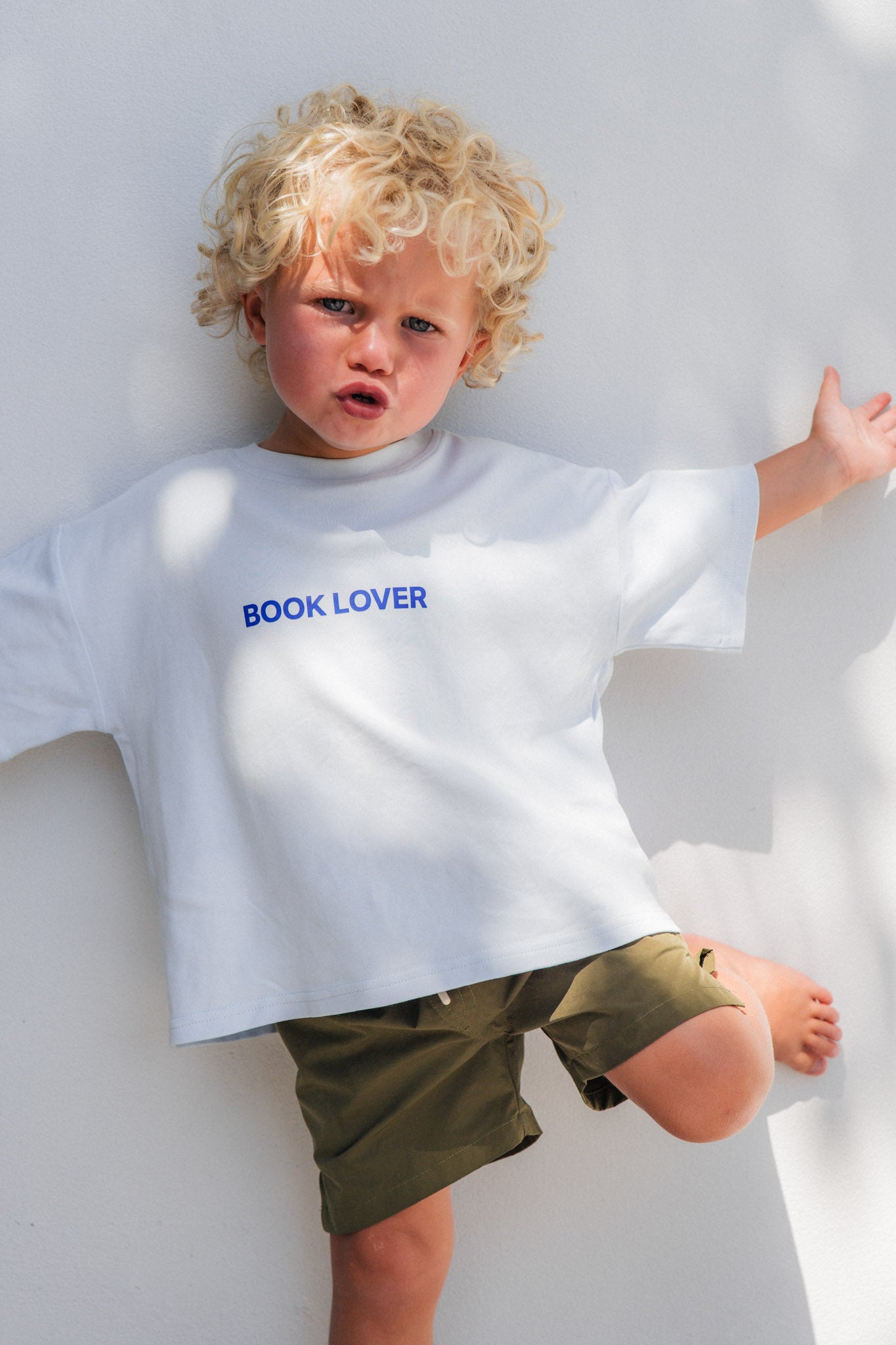 Child wearing a white t-shirt with 'BOOK LOVER' text on a white background
