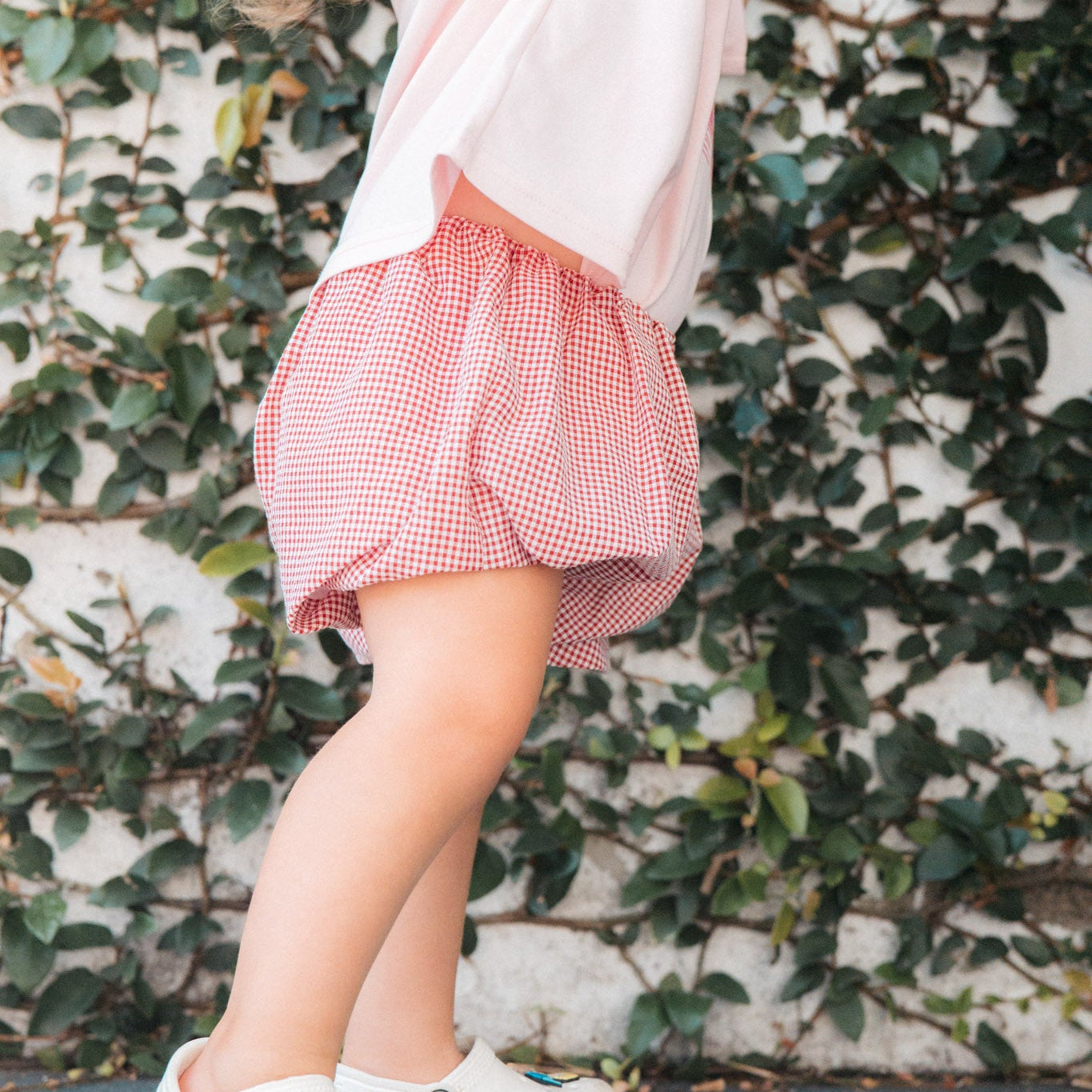 Person wearing a red checkered shorts  against a leafy background