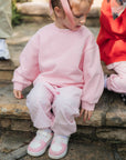 Child wearing a pink outfit sitting on stone steps.