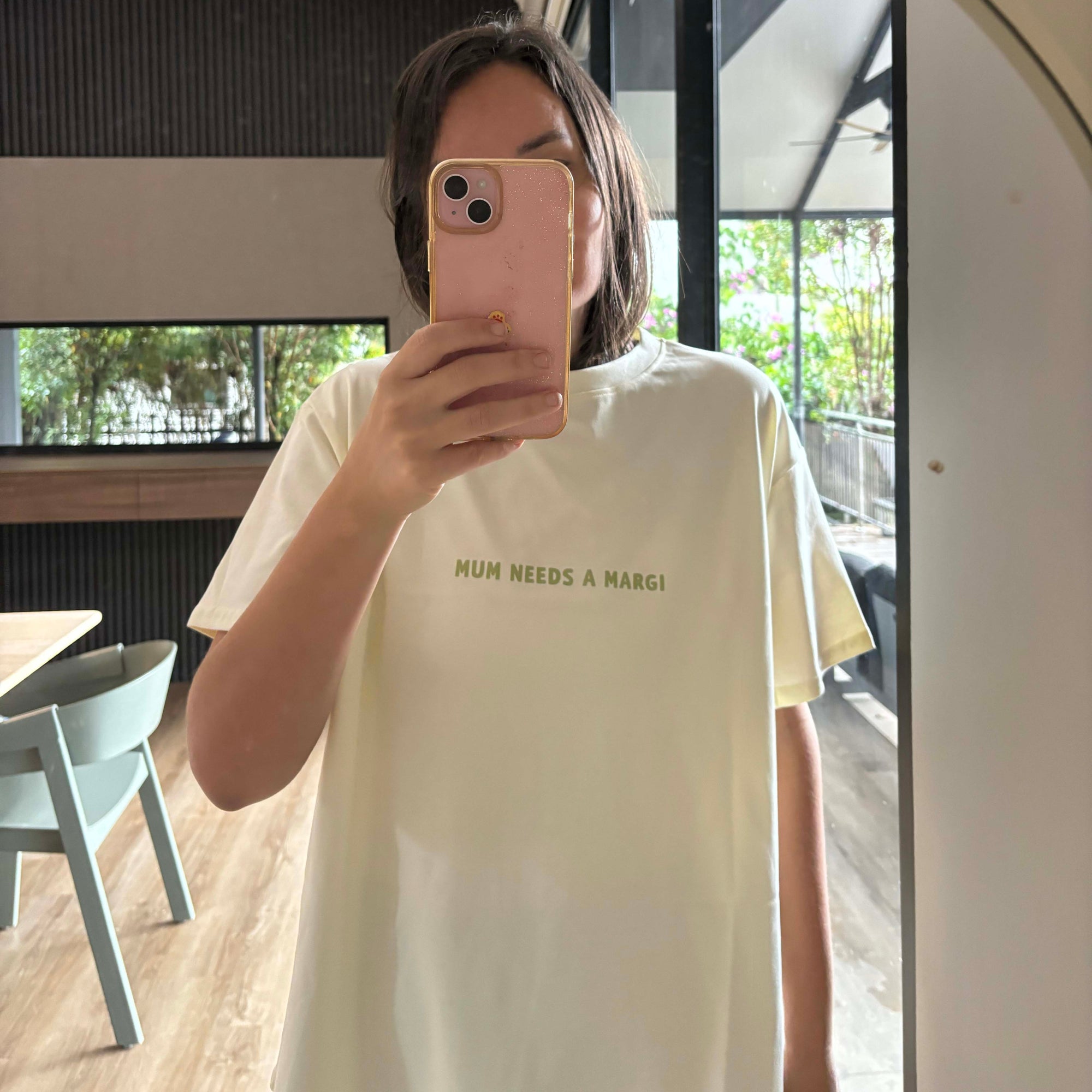 Woman taking a mirror selfie wearing a yellow t-shirt with Mum needs a margi print