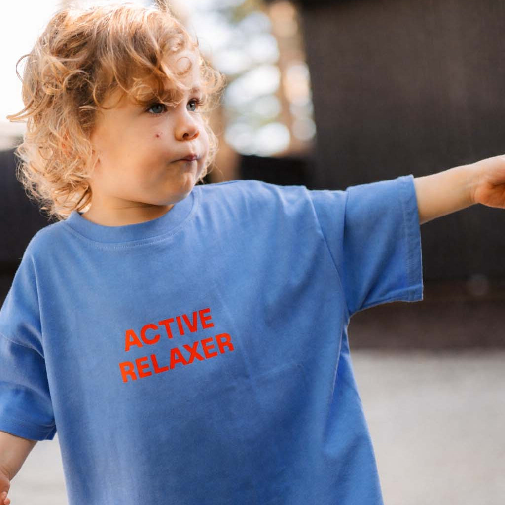 Child wearing a blue t-shirt with 'ACTIVE RELAXER' text outdoors.