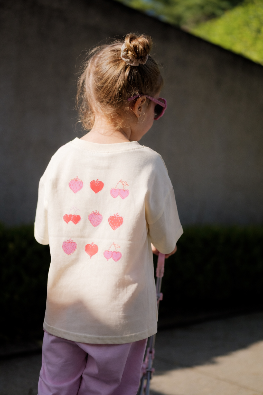 Child wearing a white shirt with pink heart patterns outdoors
