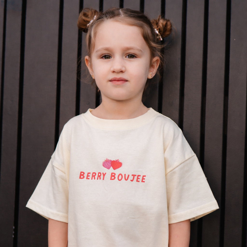 Child wearing a white t-shirt with 'Berry Boujee' text and red graphics against a dark background