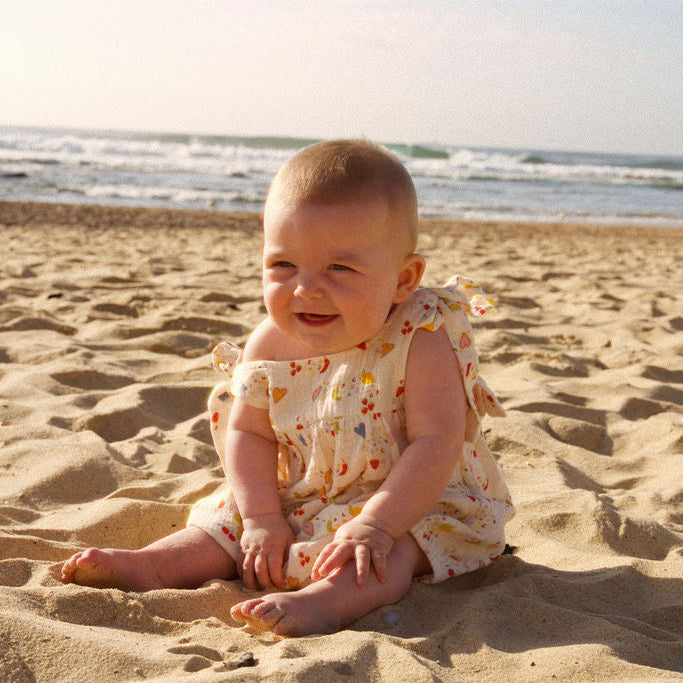 Baby sitting on a sandy beach with ocean in the background