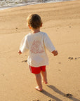 Child walking on a sandy beach with ocean waves in the background