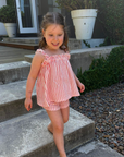 Young girl in a pink striped outfit standing on outdoor steps.