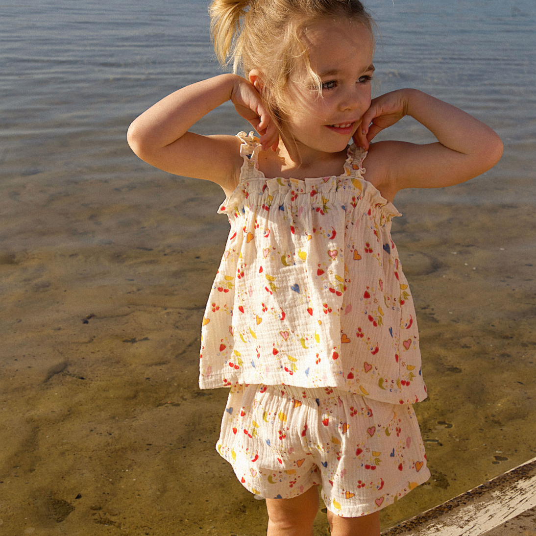 Young girl in a floral set standing by water.