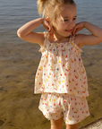 Young girl in a floral set standing by water.