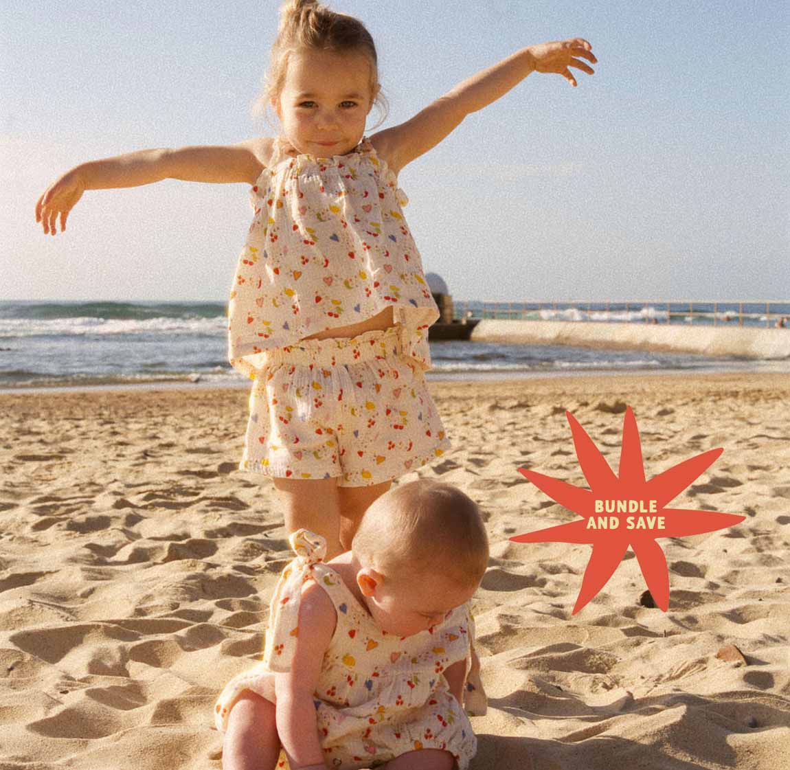 Two children in matching outfits on a beach with a 'Bundle and Save' graphic overlay.