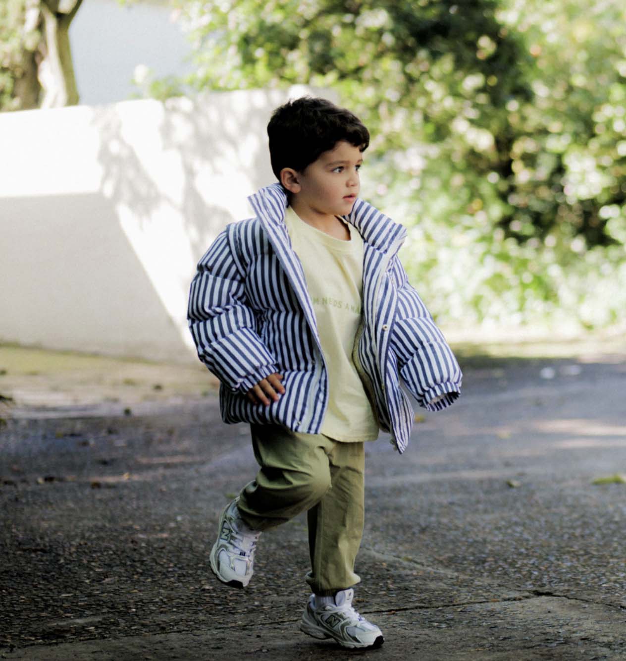 Child wearing a striped jacket outdoors with a blurred background