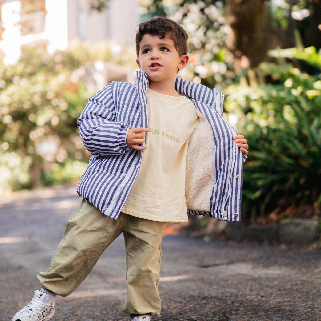 Child wearing a striped puffer jacket in an outdoor setting