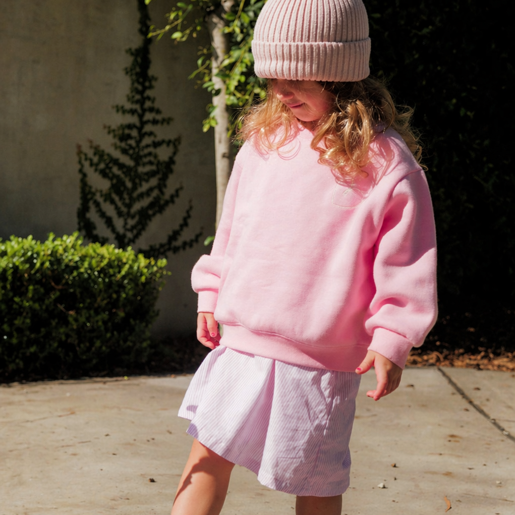 Child wearing a pink outfit with a matching hat in an outdoor setting
