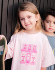 Two children, a girl holding a skateboard and a boy in the background, against a dark background.