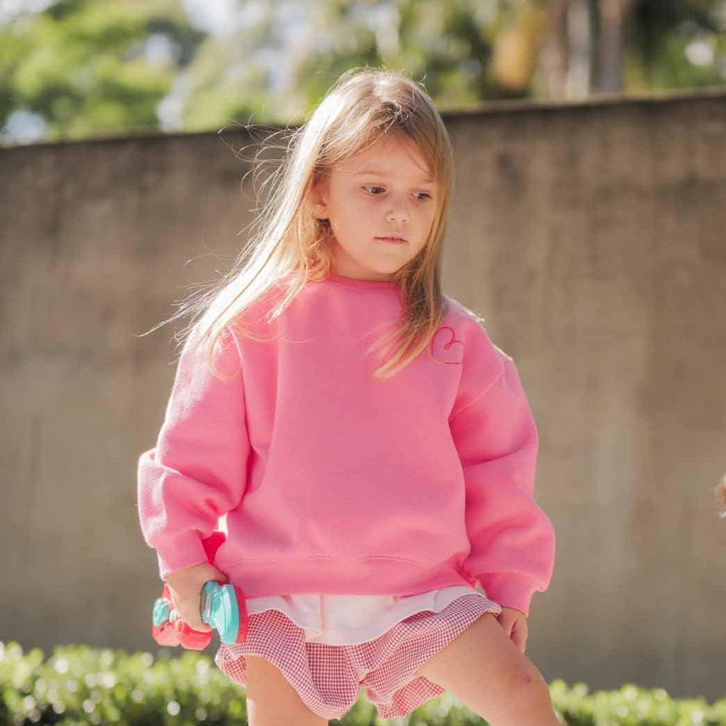 A girl in a pink sweatshirt and shorts.