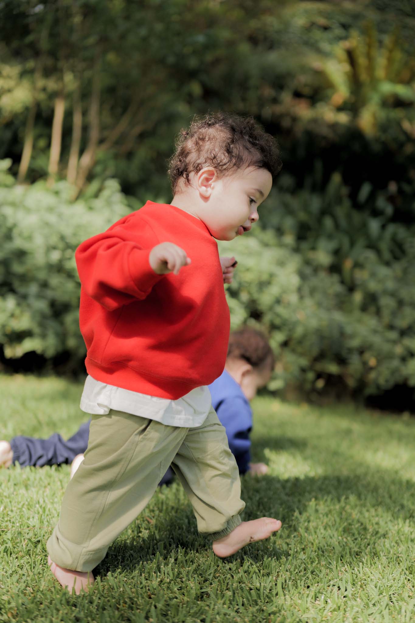 Child in a red sweater playing outdoors on grass